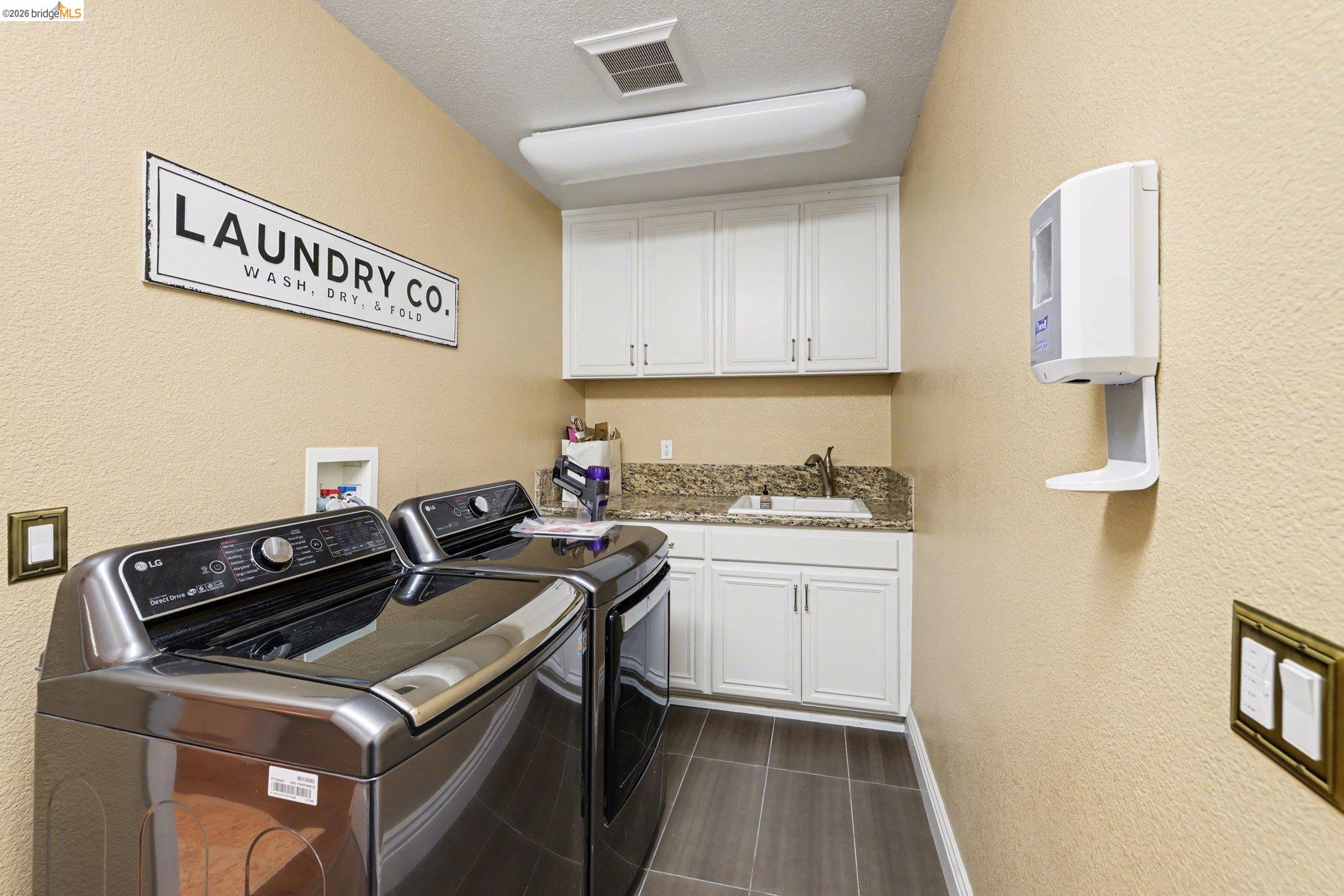 550 Rutherford Circle Brentwood, CA 94513 - Photo 11 of 28 Laundry room featuring a textured wall, washing machine and dryer, a textured ceiling, and cabinet space