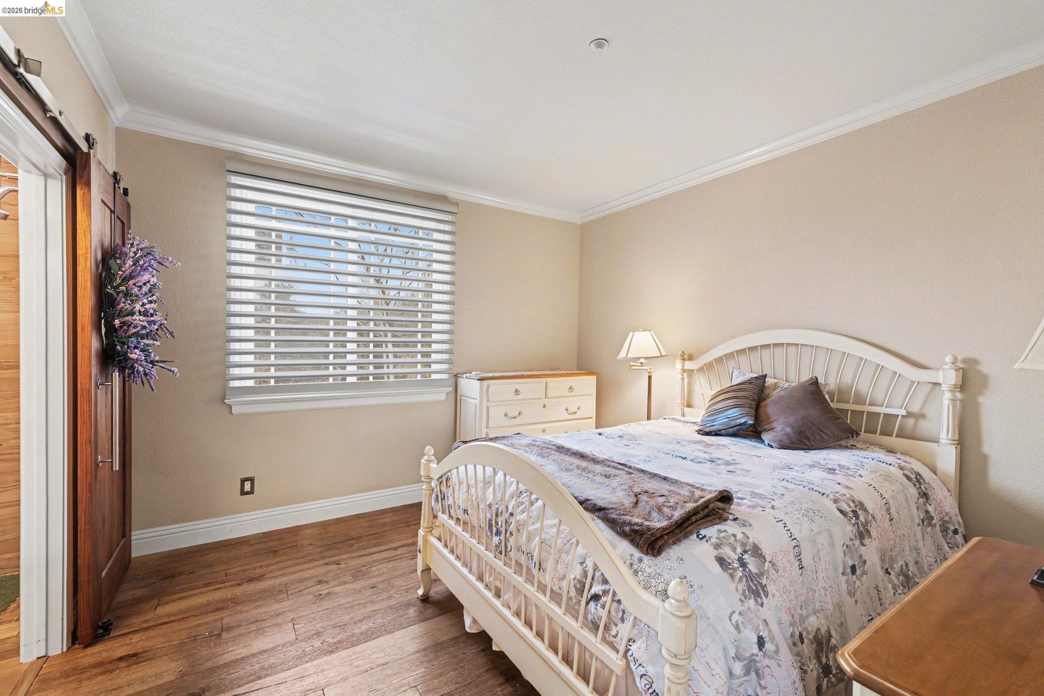 550 Rutherford Circle Brentwood, CA 94513 - Photo 12 of 28 Bedroom with hardwood / wood-style flooring, crown molding, and a barn door
