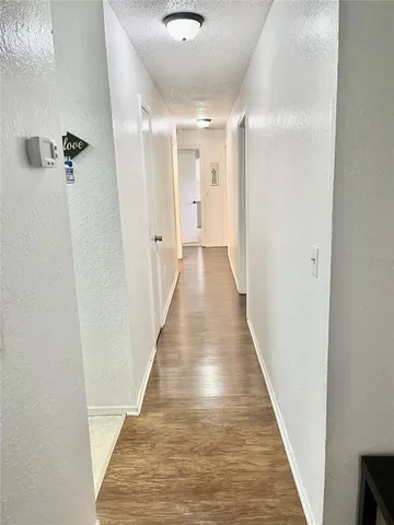 a view of a hallway with wooden floor and a bathroom