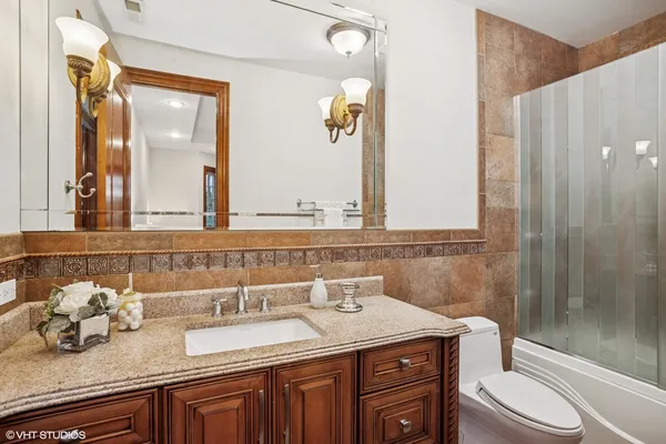 a bathroom with a granite countertop sink a toilet a mirror and shower