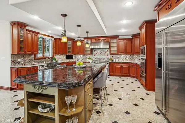 a kitchen with stainless steel appliances kitchen island granite countertop a table chairs and a refrigerator