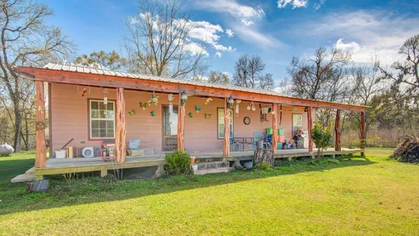 a view of a house with a yard and large trees