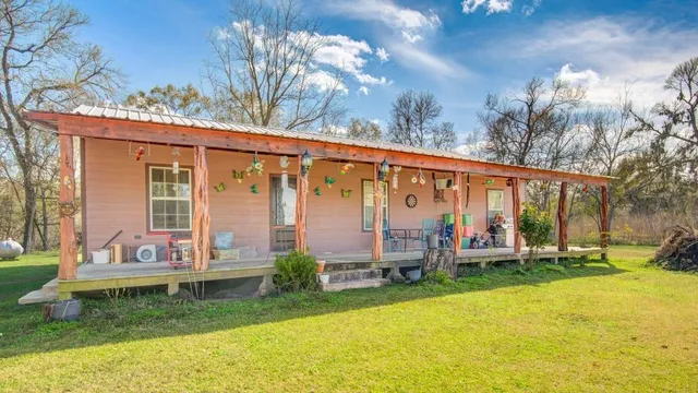a view of a house with a yard and large trees