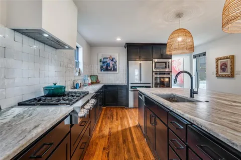 a kitchen with stainless steel appliances granite countertop a stove a sink and a microwave
