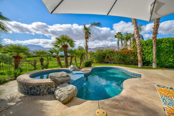 a backyard of a house with table and chairs plants and large trees