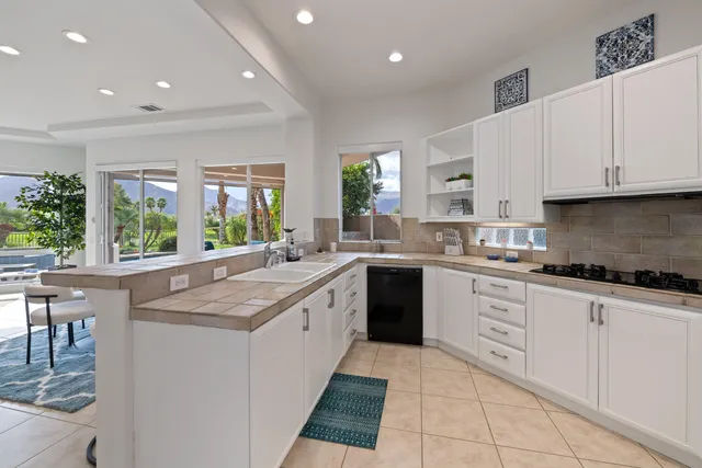 a kitchen with granite countertop a sink window and cabinets
