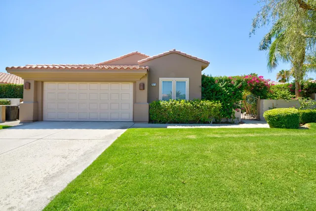 a front view of a house with a garden and garage