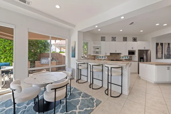 a kitchen with stainless steel appliances kitchen island granite countertop a stove a sink a dining table and chairs