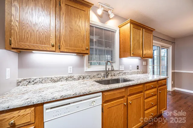 a kitchen with granite countertop stainless steel appliances wooden cabinets and a sink