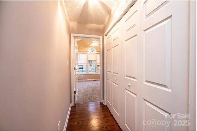 a view of a hallway with wooden floor and a bathroom