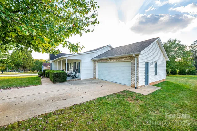 a view of a yard in front of a house with plants and large tree