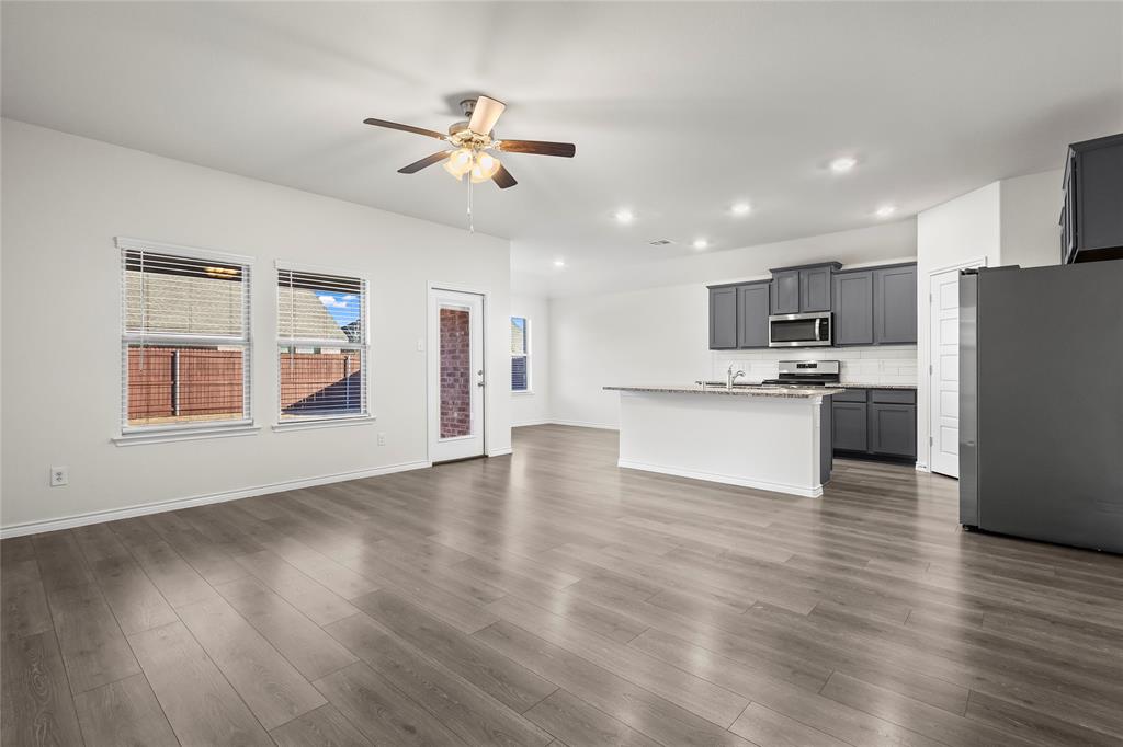 812 Indigo Road Princeton, TX 75407 - Photo 18 of 28 a view of kitchen with refrigerator microwave and wooden floor
