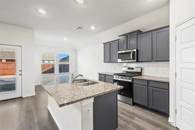 a kitchen with kitchen island granite countertop stainless steel appliances and wooden cabinets