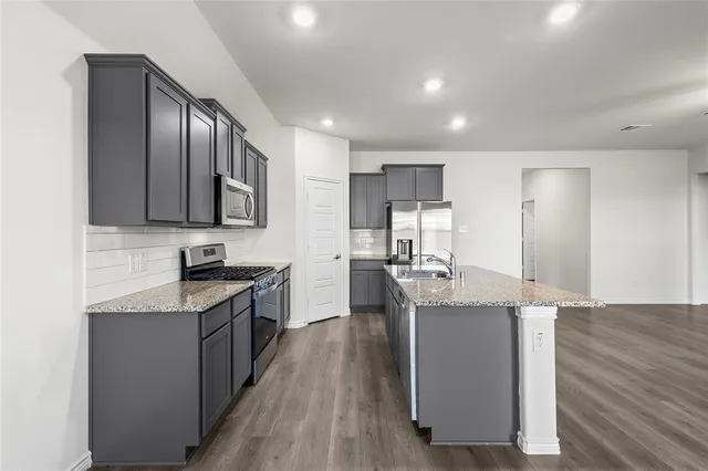 a kitchen with stainless steel appliances granite countertop a sink stove refrigerator and cabinets