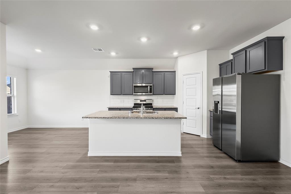 812 Indigo Road Princeton, TX 75407 - Photo 24 of 28 a kitchen with stainless steel appliances granite countertop a sink stove and refrigerator