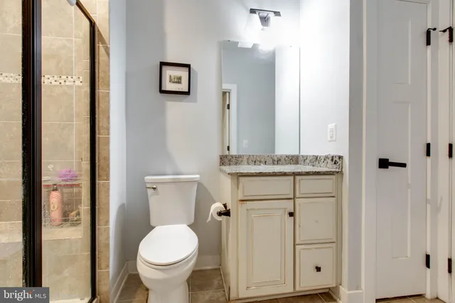 a bathroom with a granite countertop toilet sink and mirror