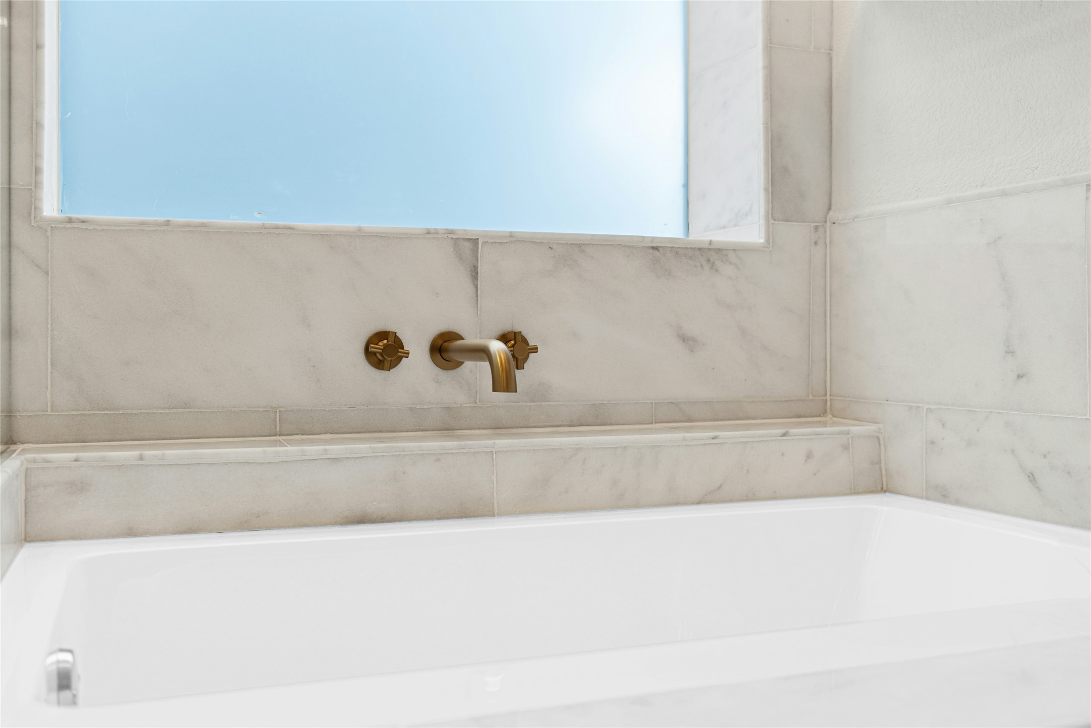 813 Caribou Ridge Trail Pflugerville, TX 78660 - Photo 29 of 39 Spa-inspired soaking tub with marble surround and designer brushed-gold wall-mounted fixtures in the luxury primary bathroom.
