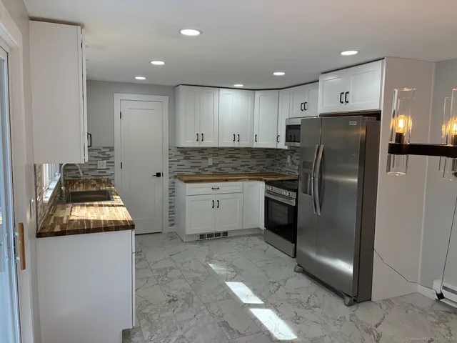 a kitchen with stainless steel appliances granite countertop a refrigerator a stove and a sink