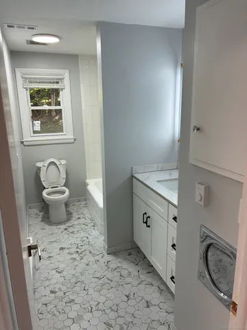 a bathroom with a granite countertop sink a toilet and a mirror