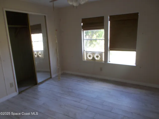 an empty room with wooden floor and windows