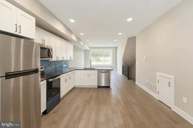 a large kitchen with a center island wooden floor stainless steel appliances and windows