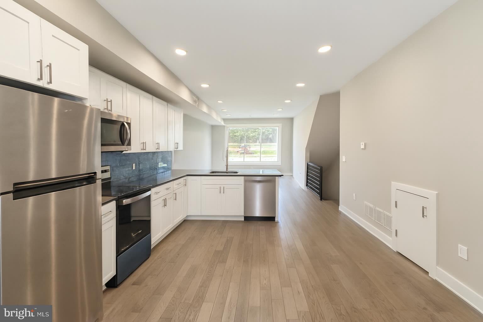 a large kitchen with a center island wooden floor stainless steel appliances and windows
