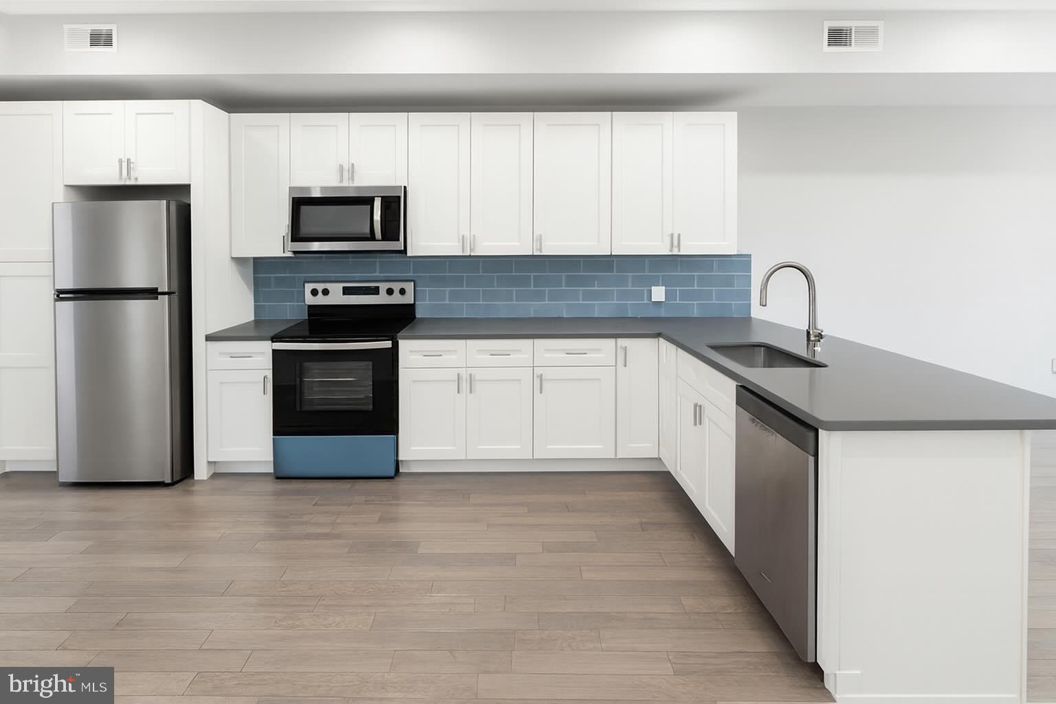 1407 North 8th Street, Unit A2 Philadelphia, PA 19122 - Photo 2 of 14 a kitchen with stainless steel appliances granite countertop a sink and a refrigerator