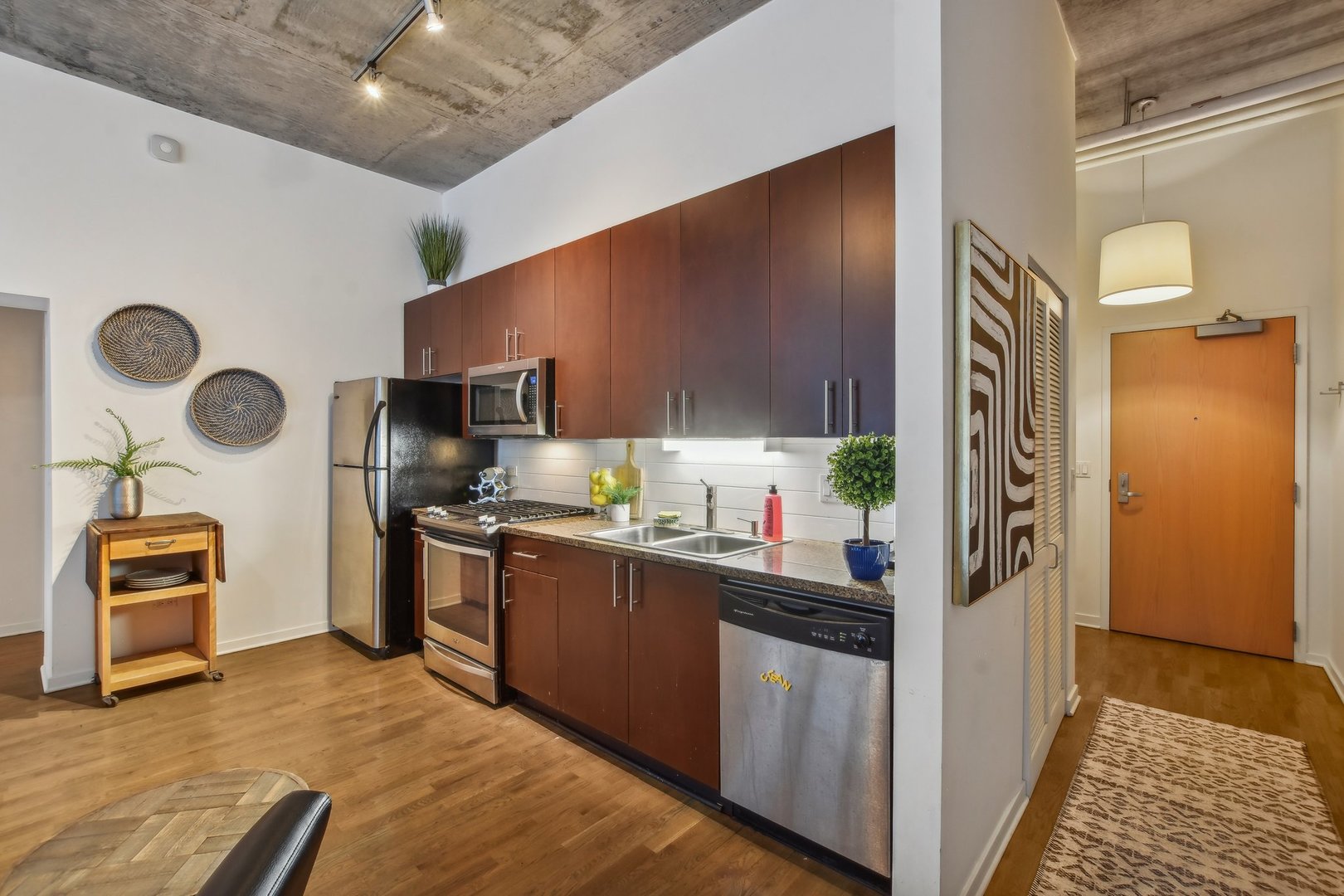 611 South Wells Street, Unit 702 Chicago, IL 60607 - Photo 13 of 32 a kitchen with stainless steel appliances granite countertop a refrigerator a stove and a sink with wooden floor