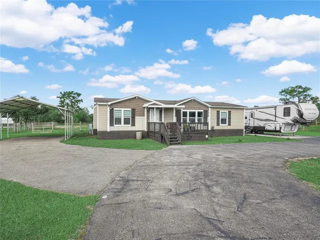 a view of house with a big yard plants and large trees