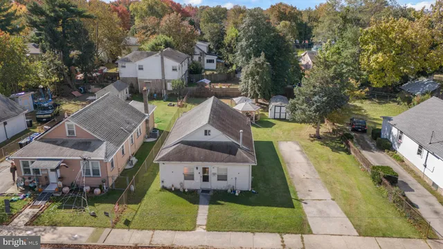 an aerial view of a house with swimming pool and large trees