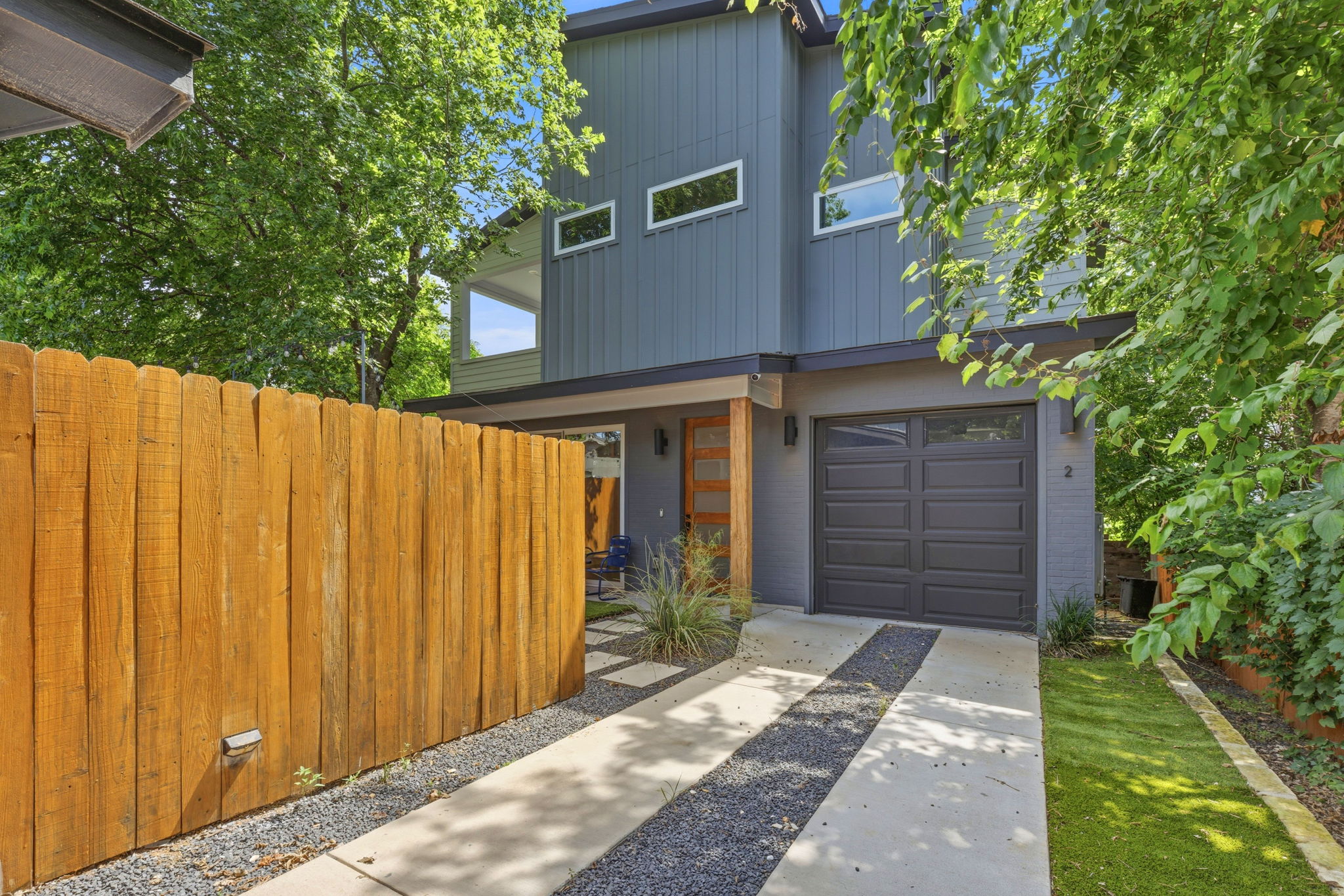 A modern two-story home with a contemporary garage door and a welcoming wooden entry.