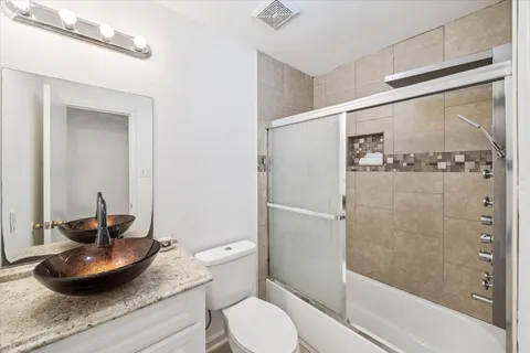 a bathroom with a granite countertop sink a toilet and shower