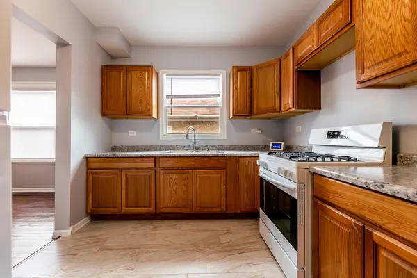 a kitchen with granite countertop a sink stove and cabinets