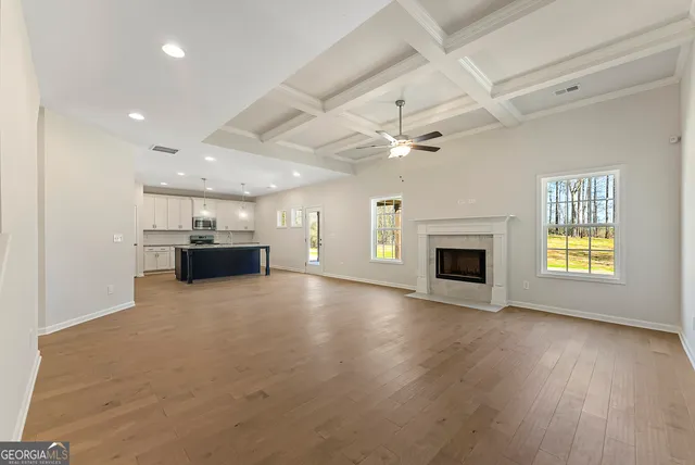 an empty room with kitchen fireplace and a ceiling fan