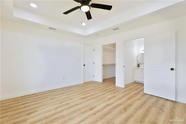 an empty room with wooden floor and ceiling fan
