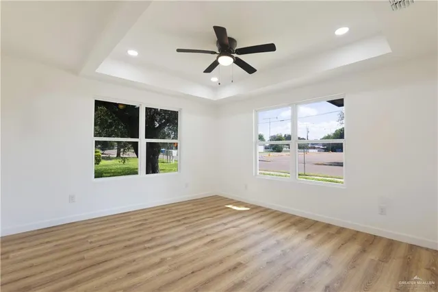 a view of an empty room with a window and wooden floor