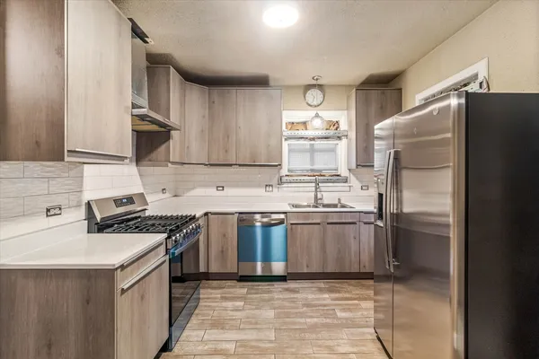 a kitchen with stainless steel appliances granite countertop a sink stove refrigerator and cabinets