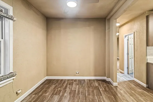 a view of an empty room with wooden floor and a window