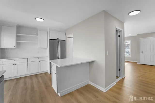 a kitchen with white cabinets and wooden floor