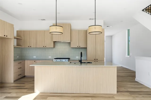 a kitchen with stainless steel appliances granite countertop a sink a refrigerator a stove and white cabinets with wooden floor