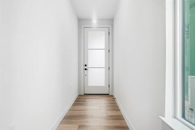 a view of a hallway with wooden floor and a bathroom