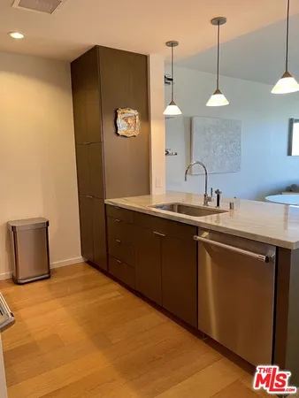 a kitchen with stainless steel appliances granite countertop a sink a refrigerator and a wooden floor