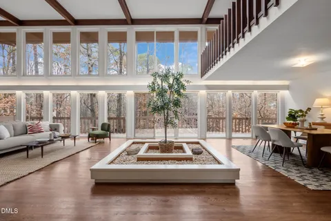 a living room with furniture large windows and wooden floor