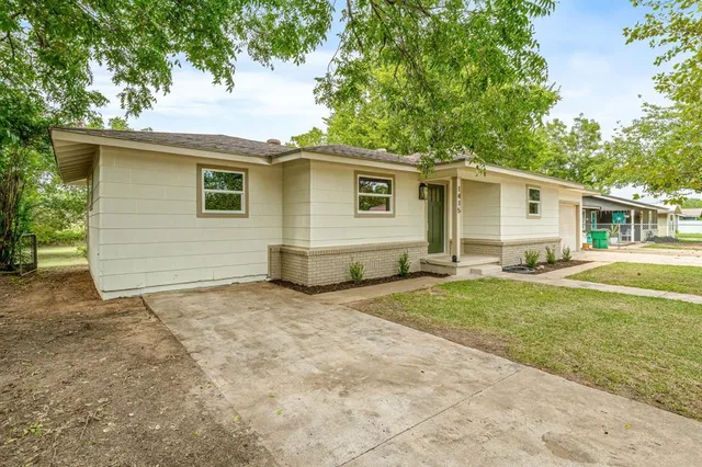 a view of a house with a yard and large tree