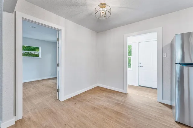 an empty room with wooden floor and a hallway