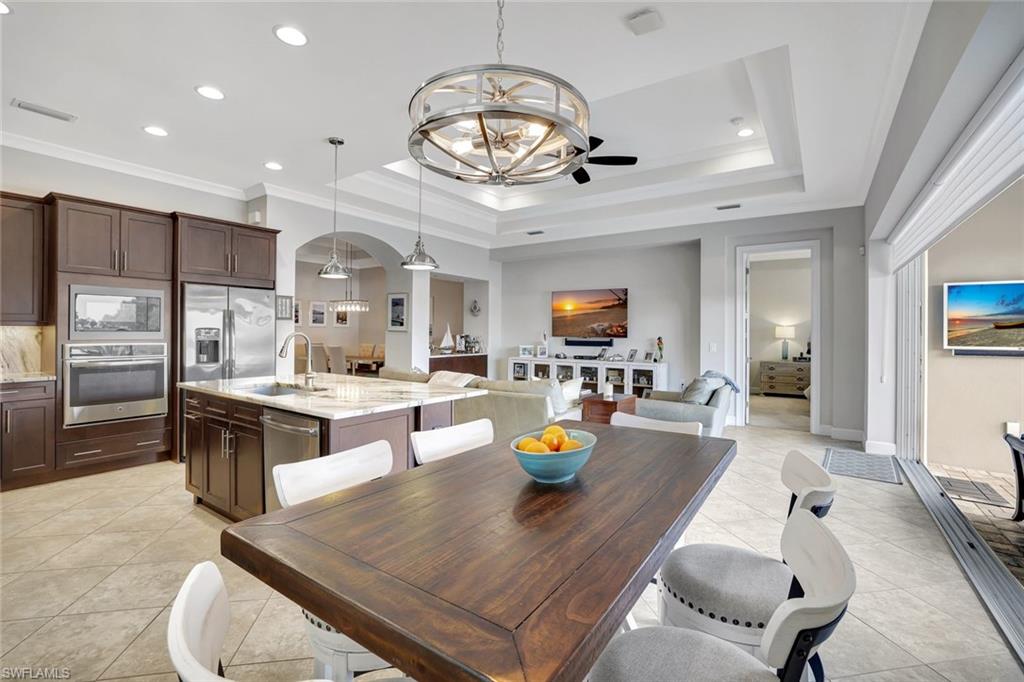 4905 Andros Drive Naples, FL 34113 - Photo 17 of 45 Dining room featuring a chandelier, arched walkways, recessed lighting, light tile and crown molding
