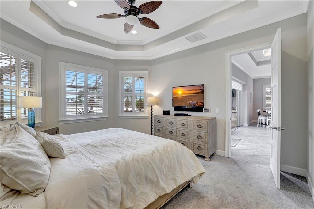 4905 Andros Drive Naples, FL 34113 - Photo 35 of 45 Owners Suite with crown molding, light carpet, a ceiling fan, and a tray ceiling