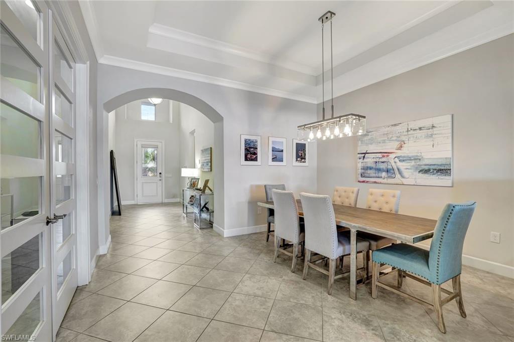 4905 Andros Drive Naples, FL 34113 - Photo 39 of 45 Dining space featuring arched walkways, a raised ceiling, crown molding
