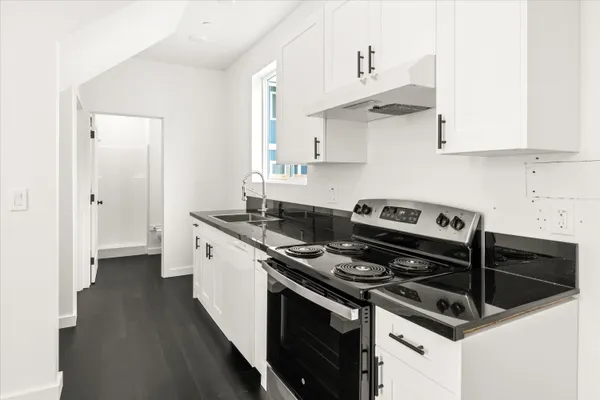 a kitchen with stainless steel appliances a sink dishwasher a stove and white cabinets