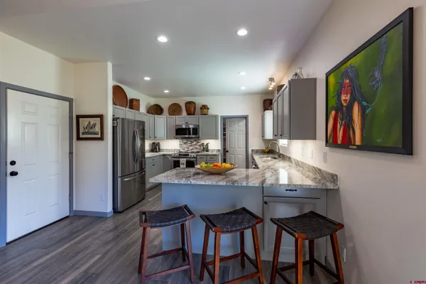 a kitchen with stainless steel appliances a dining table chairs refrigerator and sink